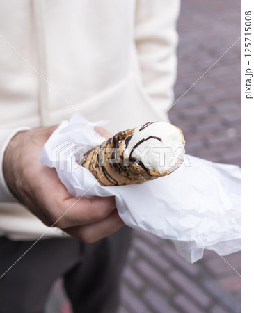 Hands Holding Cannoli Dessert, Traditional Sicilian Pastry, Tube-shaped Shell Of Fried Pastry Dough, Filled With A Sweet, Creamy Filling Containing Ricotta Cheese. Man Holds Street Food. Vertical. 125715008