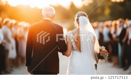 father walks his daughter down aisle during beautiful sunset, surrounded by guests. emotional moment captures love and joy on this special day 125717313