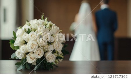 beautiful bridal bouquet of white roses on table, with couple in background. scene captures essence of love and celebration, perfect for weddings 125717562