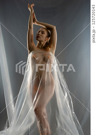 Red naked woman with gold bodyart posing dramatically inside a large film 125720143