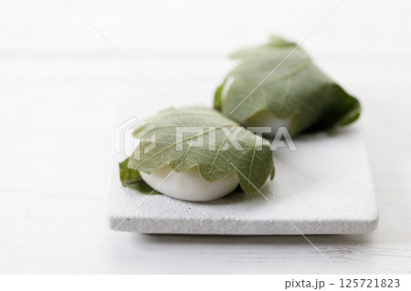 Closeup of Kashiwa mochi. Traditional Japanese sweet from white mochi or rice cake and sweet Anko or red bean paste filling surrounded with Kashiwa or Oak leaf . Closeup of Kashiwa mochi. Traditional Japanese sweet from white mochi or rice cake and sweet Anko or red bean paste filling surrounded with Kashiwa or Oak leaf . 125721823