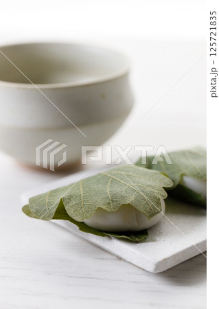 Kashiwa mochi and Cup of fresh matcha tea. Japanese sweet from mochi or rice cake and sweet red bean paste filling surrounded with Kashiwa or Oak leaf . Kashiwa mochi and Cup of fresh matcha tea. Japanese sweet from mochi or rice cake and sweet red bean paste filling surrounded with Kashiwa or Oak leaf . 125721835