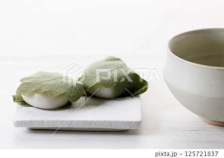 Kashiwa mochi and Cup of fresh matcha tea. Japanese sweet from mochi or rice cake and sweet red bean paste filling surrounded with Kashiwa or Oak leaf . 125721837