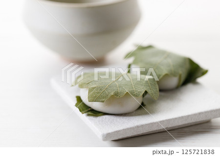 Kashiwa mochi and Cup of fresh matcha tea. Japanese sweet from mochi or rice cake and sweet red bean paste filling surrounded with Kashiwa or Oak leaf . Kashiwa mochi and Cup of fresh matcha tea. Japanese sweet from mochi or rice cake and sweet red bean paste filling surrounded with Kashiwa or Oak leaf . 125721838