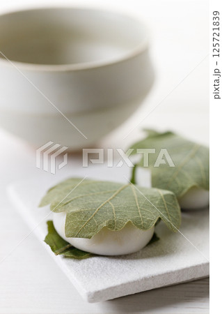 Kashiwa mochi and Cup of fresh matcha tea. Japanese sweet from mochi or rice cake and sweet red bean paste filling surrounded with Kashiwa or Oak leaf . Kashiwa mochi and Cup of fresh matcha tea. Japanese sweet from mochi or rice cake and sweet red bean paste filling surrounded with Kashiwa or Oak leaf . 125721839