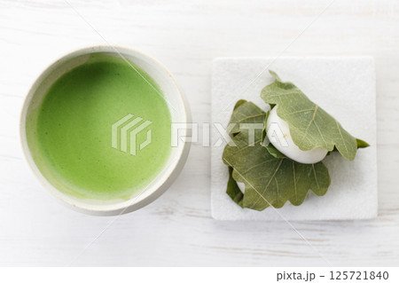 Kashiwa mochi and Cup of fresh matcha tea. Japanese sweet from mochi or rice cake and sweet red bean paste filling surrounded with Kashiwa or Oak leaf . 125721840
