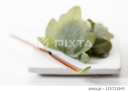 Closeup of Chashaku or tea scoop, equipments for preparing matcha green tea and Kashiwa mochi, Traditional Japanese sweet. Closeup of Chashaku or tea scoop, equipments for preparing matcha green tea and Kashiwa mochi, Traditional Japanese sweet. 125721845