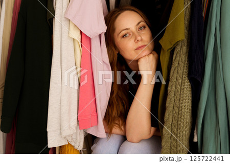 Woman can't decide what to wear, closet with too many clothing. Overburdened with clothes Woman can't decide what to wear, closet with too many clothing. Overburdened with clothes 125722441