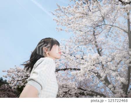 満開の桜と春風を感じる少女 125722468