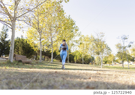Young sportswoman running in a park during a sunny autumn day 125722940