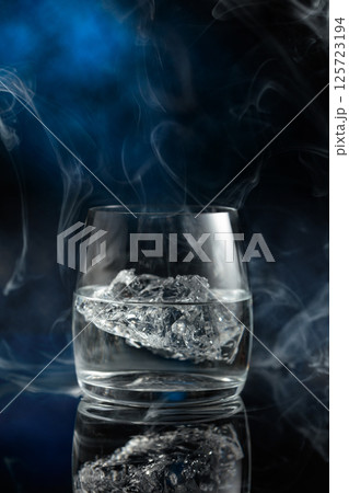 Vodka with ice on a black reflective background. Vodka with ice on a black reflective background. 125723194