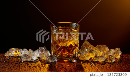 Whiskey and ice on a black wet table. Whiskey and ice on a black wet table. 125723209