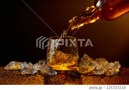 Whiskey pours from bottle to glass. Whiskey pours from bottle to glass. 125723210