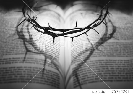 A crown of thorns symbolizing the sacrifice and suffering of Jesus Christ on the cross and a heart shadow reflected on a Bible, Holy Week background A crown of thorns symbolizing the sacrifice and suffering of Jesus Christ on the cross and a heart shadow reflected on a Bible, Holy Week background 125724201