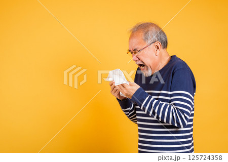 Portrait senior old man blowing nose with tissue studio shot isolated on yellow background, Asian elder man cold having flu and sneezing from sickness virus problem use tissue, pensioner unwell Portrait senior old man blowing nose with tissue studio shot isolated on yellow background, Asian elder man cold having flu and sneezing from sickness virus problem use tissue, pensioner unwell 125724358