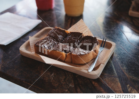 Enjoy a Delicious Slice of Toast Topped with Creamy Chocolate Spread on a Rustic Wooden Tray 125725519