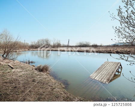 A Serene Pond Accompanied by An Abandoned Dock Nestled Within A Tranquil Natural Landscape 125725808
