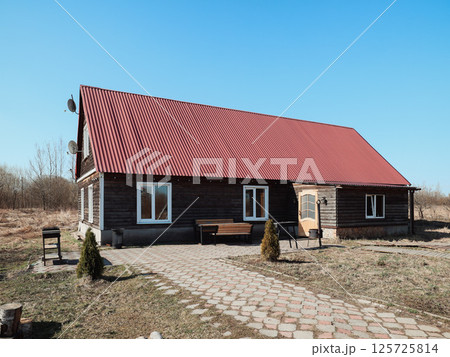 Charming Wooden House featuring a Vibrant Red Roof Set Against a Scenic Landscape Backdrop 125725814