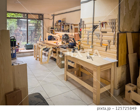 Spacious woodworking studio with tables, frames, tool racks, bright walls, power saws, and crafting stations ready for construction and DIY building 125725849