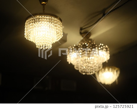 Elegant Chandeliers are Beautifully Illuminating a Dimly Lit Room with a Warm Atmosphere Elegant Chandeliers are Beautifully Illuminating a Dimly Lit Room with a Warm Atmosphere 125725921