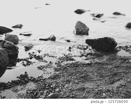 Serene Shoreline Beautifully Positioned Rocks on a Tranquil Water Edge of the Coast 125726030
