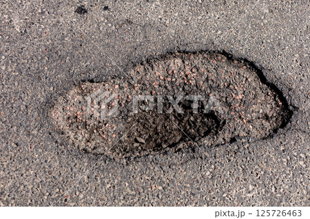 Large hole in the asphalt is evident on the highway, indicating significant damage that requires urgent repair to ensure safety for all vehicles 125726463