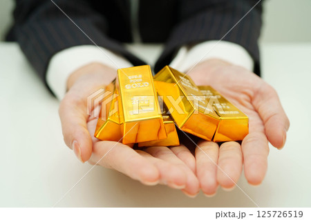 Asian woman holding gold bar in finance business. Asian woman holding gold bar in finance business. 125726519