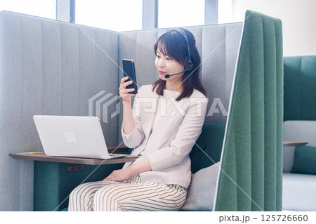 リモート会議をサボってスマホを使う若いビジネスパーソン リモート会議をサボってスマホを使う若いビジネスパーソン 125726660