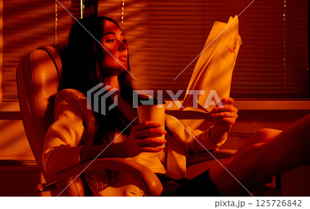 Businesswoman Relaxing with Documents and Coffee After Work. Businesswoman Relaxing with Documents and Coffee After Work. 125726842
