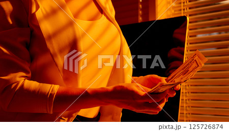 Female Entrepreneur Holding Cash near Window Blinds. 125726874