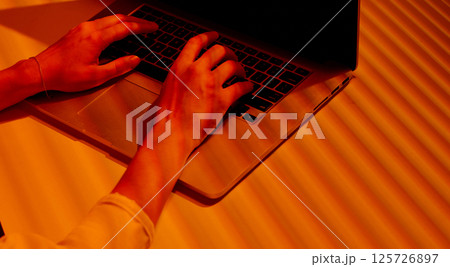 Female Hands Typing on Laptop in Sunset Office Light. Female Hands Typing on Laptop in Sunset Office Light. 125726897