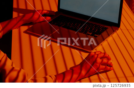 Woman Using Laptop and Mouse in Sunset Shadow Light. Woman Using Laptop and Mouse in Sunset Shadow Light. 125726935