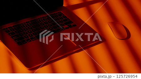 Modern Laptop and Mouse in Dramatic Orange Light. 125726954