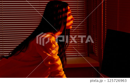 Focused Woman Working at Computer in Warm Office Light. 125726963