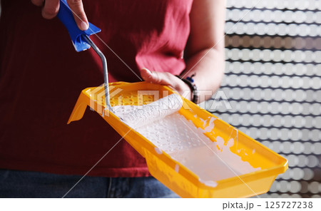 Girl Painting With White Paint Using A Roller And A Brush With A Yellow Paint Tray Girl Painting With White Paint Using A Roller And A Brush With A Yellow Paint Tray 125727238