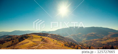 Mountain landscape on a sunny autumn day. View of the mountain slopes and dirt road. Beautiful nature landscape. Carpathian mountains. Ukraine. Horizontal banner 125727665