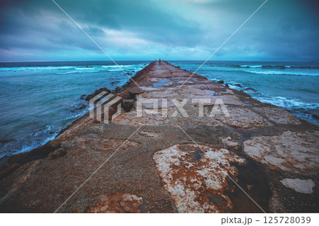 Seascape in the evening. A stone breakwater in the ocean. Costa da Caparica, Almada, Portugal 125728039
