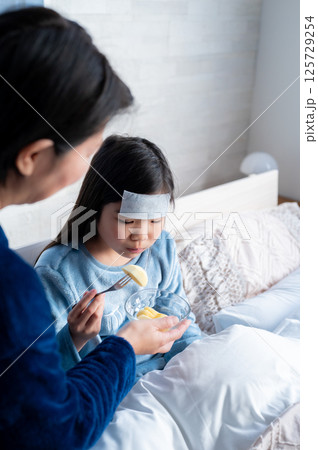 病気の娘に食事を与えながら見守る母親の優しい表情 125729254