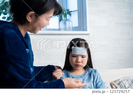 おかゆを食べながら母親のサポートを受ける病気の子ども 125729257