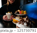 Woman Enjoying Coffee and Tiered Pastries 125730791