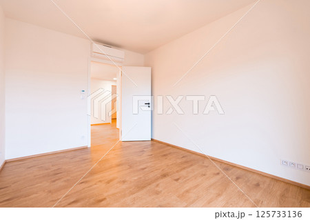 Spacious and bright room in an empty apartment, highlighting wooden flooring and crisp white walls. Spacious and bright room in an empty apartment, highlighting wooden flooring and crisp white walls. 125733136