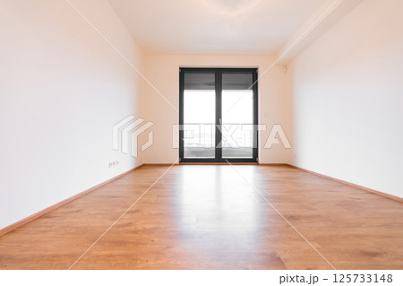 A bright, vacant room in a sleek apartment featuring wooden flooring, a tilt and turn window system A bright, vacant room in a sleek apartment featuring wooden flooring, a tilt and turn window system 125733148