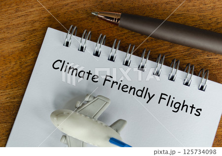 Top view of Climate Friendly Flight text on white notepad with small airplane and pen background. Environmental awareness Top view of Climate Friendly Flight text on white notepad with small airplane and pen background. Environmental awareness 125734098