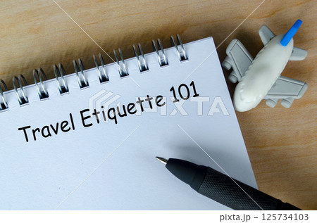 Travel Etiquette 101 text on white notepad with airplane and black pen background 125734103
