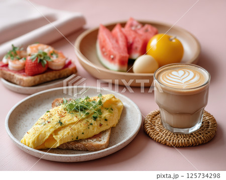 Soft pastel themed healthy brunch with shrimp toast, egg omelette on bread, fresh fruit plate, and latte coffee on pink table 125734298
