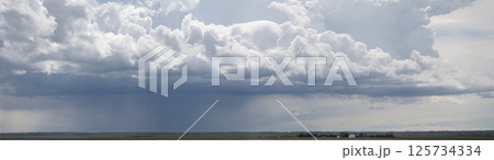Dark clouds gathering over farmland with rain falling in the distance 125734334