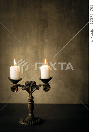 Atmospheric vintage candelabrum with burning candles on the table, vertical image, copy space. 125734763