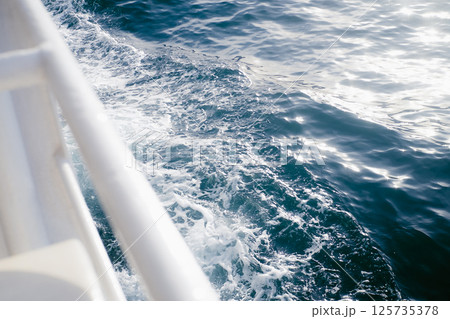 View of sea water with sun rays from the deck of a ferry View of sea water with sun rays from the deck of a ferry 125735378