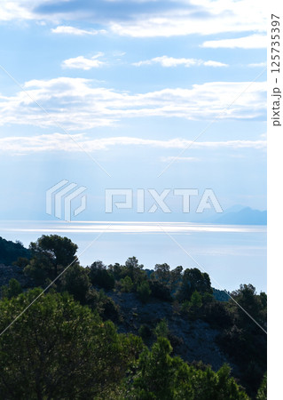 A patch of sunlight on the sea under a blue sky, view from a hill A patch of sunlight on the sea under a blue sky, view from a hill 125735397
