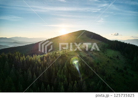 Aerial view of serene mountain landscape at sunset. Forested hills bathed in warm, golden light, creating tranquil atmosphere. Rolling hills stretch into the distance, covered in dense, lush greenery. Aerial view of serene mountain landscape at sunset. Forested hills bathed in warm, golden light, creating tranquil atmosphere. Rolling hills stretch into the distance, covered in dense, lush greenery. 125735825